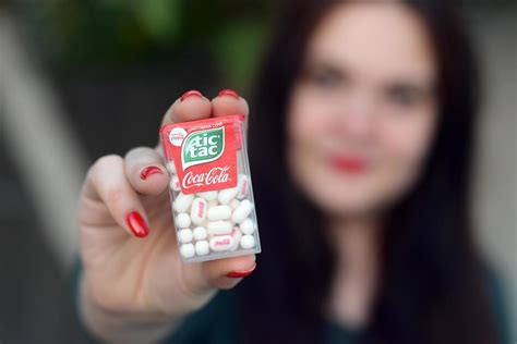 KHARKOV, UKRAINE - DECEMBER 9, 2020 Young girl holds Tic-tac hard mints pack with coca-cola ...