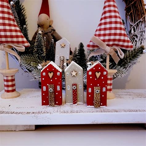 three small red and white houses sitting on top of a table next to christmas decorations