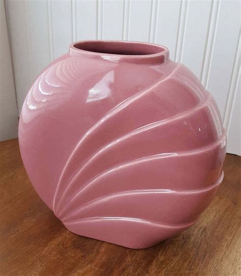 a pink vase sitting on top of a wooden table