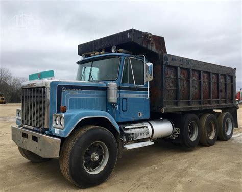 a blue dump truck parked on top of a dirt field