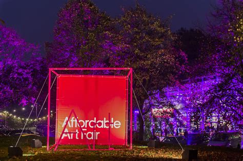 the entrance to an art fair lit up with purple lights and trees in the background