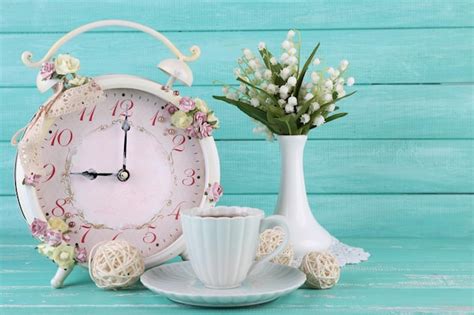 Premium Photo | Beautiful vintage alarm clock with flowers and cup of tea on blue wooden background