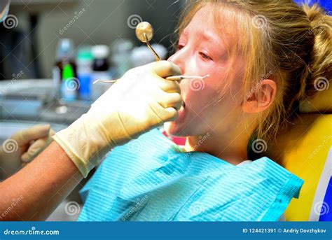 A Little Girl at the Dentist is Crying with Tears at a Doctor`s Appointment while Treating a ...