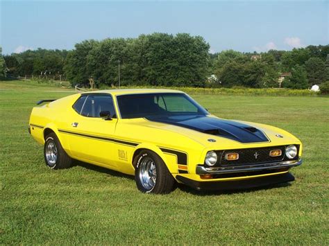 a yellow car parked on top of a lush green field