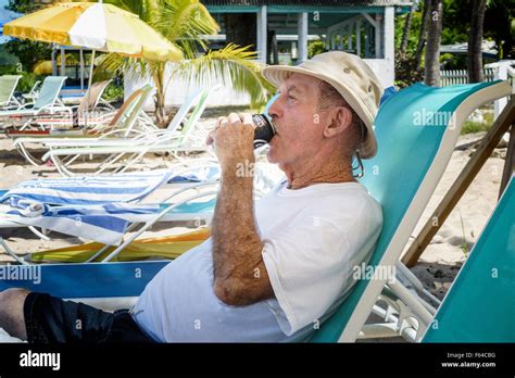 A 77 year old Caucasian man drinks a soft drink while relaxing on the ...