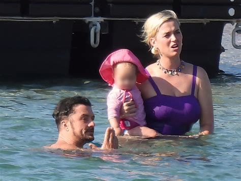 Katy Perry stuns in purple swimsuit as she hits the beach with fiancé Orlando Bloom and daughter ...