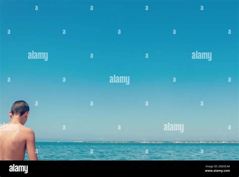 Rear of man standing on the beach. Sunny weather. Man alone with the sea Stock Photo - Alamy