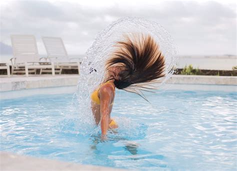 a woman is playing in the pool with her hair blowing back and feet up ...