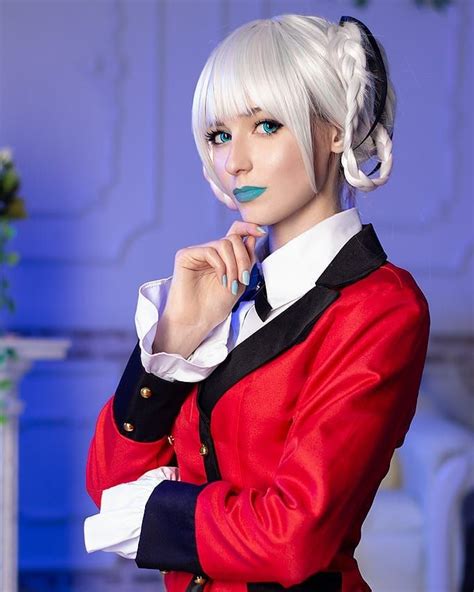 a woman with white hair and blue eyes wearing a red jacket is posing for the camera