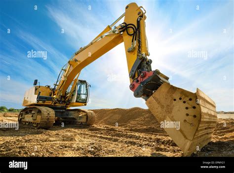 Big excavator on new construction site, in the background the blue sky and sun Stock Photo - Alamy