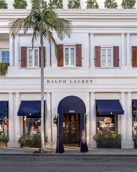 a tall white building with blue awnings and palm trees