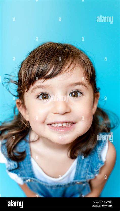 Portrait of cute little girl smiling very expressive on blue background ...