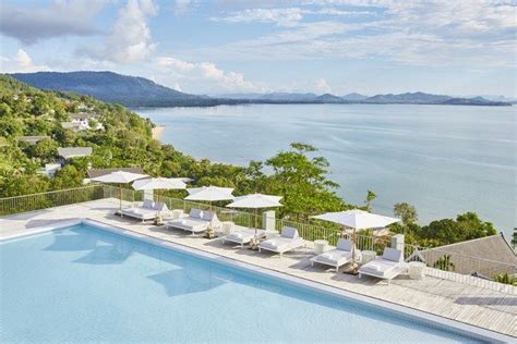 an outdoor swimming pool with lounge chairs and umbrellas next to the water's edge