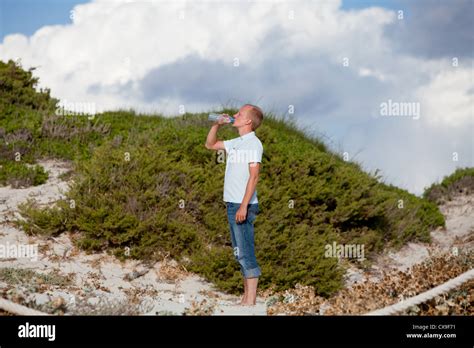 young man ist drinking water summertime dune beach sky background Stock ...