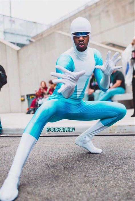 a man dressed in blue and white poses for a photo while people watch from the sidewalk