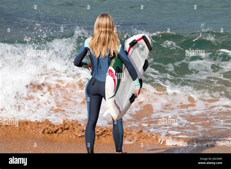 Rear view of blonde australian girl stood on a beach holding her Stock ...