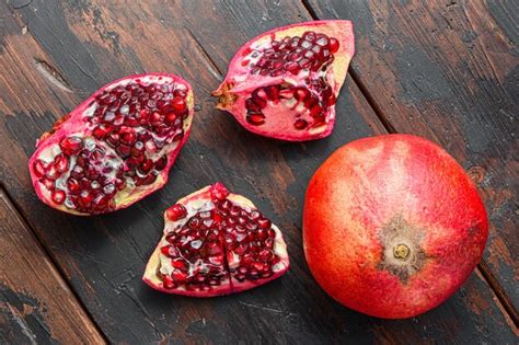 Premium Photo | Cuts of pomegranate over old dark wooden table, side ...