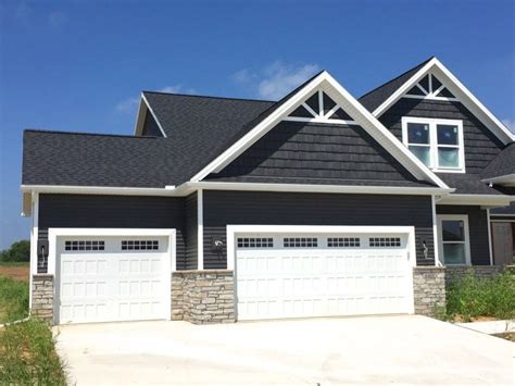 home with grey siding and dark grey shakes with black roof carriage style garage door and stone ...