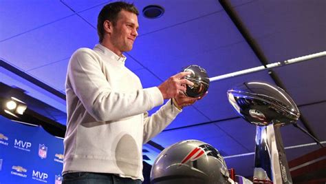 Patriots QB Tom Brady lifts his Super Bowl MVP trophy Monday.