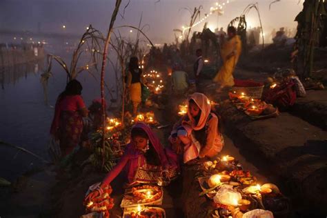 Devotees perform rituals at sunset on the banks of the Yamuna during the Chhath Puja festival in ...