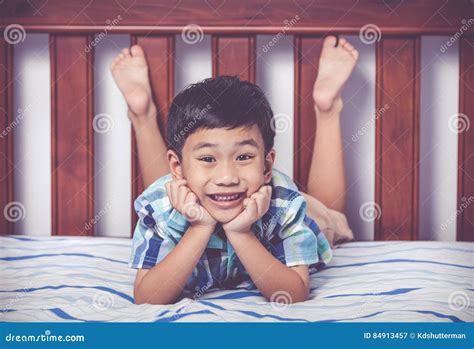 Handsome Boy Lying Barefoot on Bed in Bedroom. Happy Child Smiling. Vintage Tone Effect. Stock ...