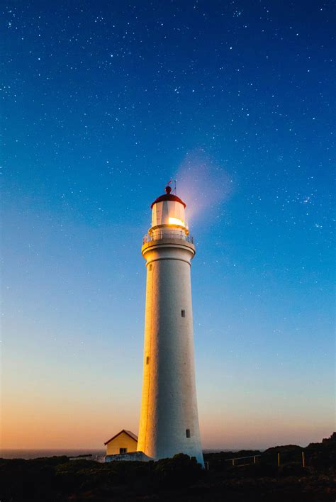 Lighthouse beneath the sky and stars with light on image - Free stock ...