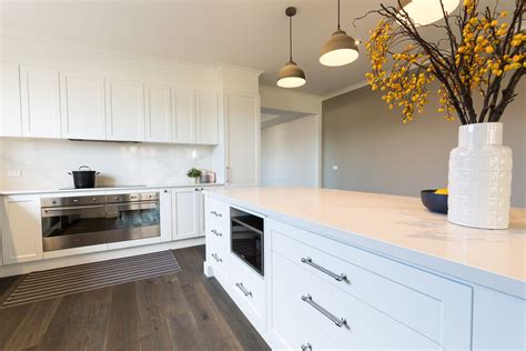 White shaker style vinyl wrap kitchen with stone bench tops and splash back