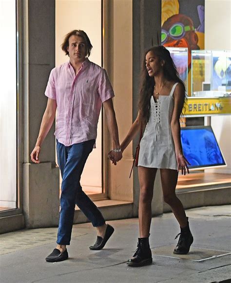 a man and woman walking down the street holding hands