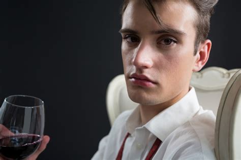 Premium Photo | Androgynous man holding wine glass against black wall