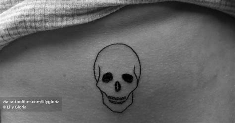 Skull tattoo hand poked on the rib, minimalistic style.