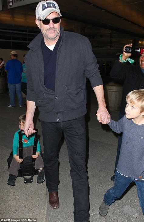 Kevin Costner gives his son a ride on his roller suitcase as he jets home with his family to LAX ...