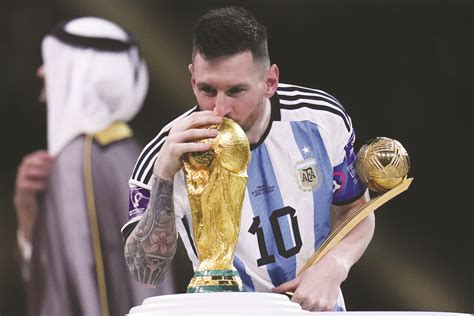 Lionel Messi kisses the FIFA World Cup trophy as he holds the Golden Ball award for best player ...