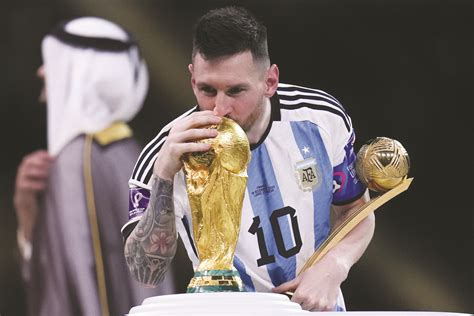 Lionel Messi kisses the FIFA World Cup trophy as he holds the Golden ...