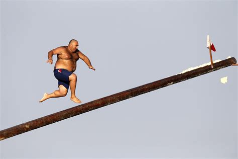 A man runs up the 'gostra', a pole covered in grease, during the religious feast of St Julian ...