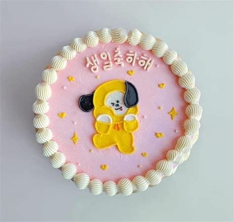 a pink cake with white frosting and a yellow teddy bear on it