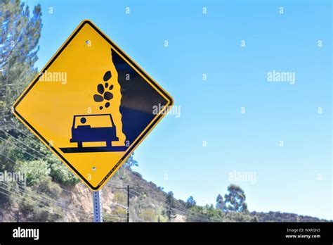 Beware of falling rocks on to car sign. Warning sign. Yellow and black Stock Photo - Alamy