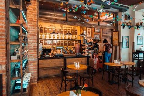 the inside of a restaurant with wooden tables and stools, decorated with paper birds