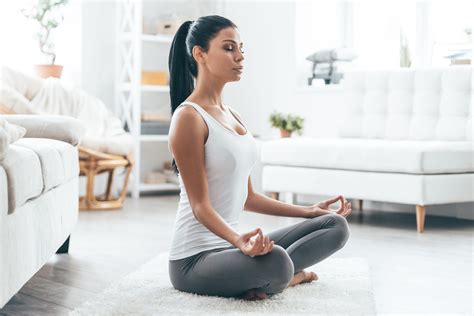 Time for yoga. Attractive young woman exercising and sitting in yoga lotus position while ...