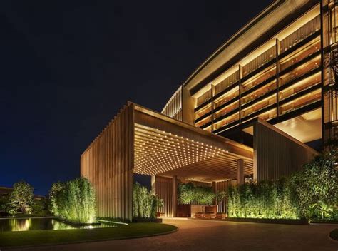 an exterior view of a hotel at night with lights on and trees in the foreground