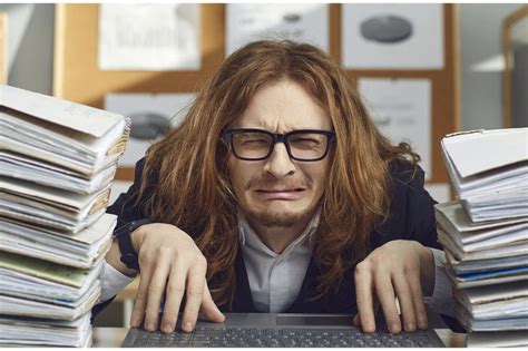 Unhappy tired employee doing paperwork and working on laptop computer. Portrait of funny sad ...