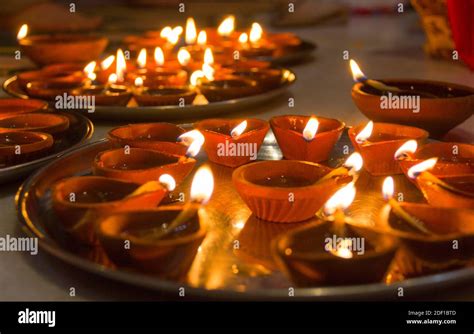 Lighting candles and clay lamps on silver trays for Diwali Hindu ...