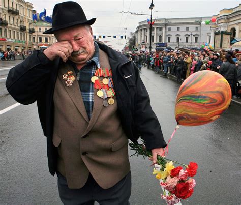 an older man walking down the street with flowers and balloons