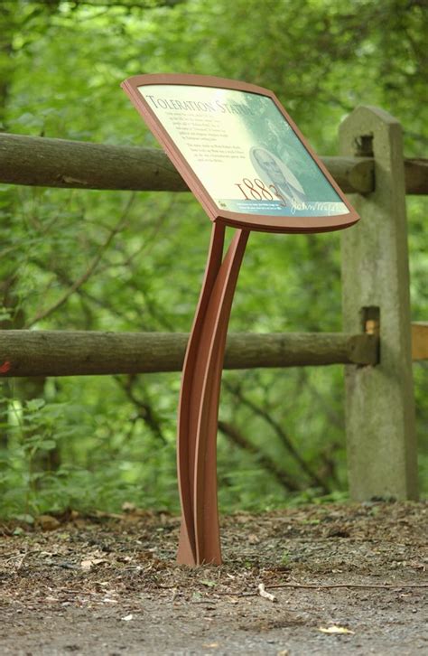 there is a sign in front of a wooden fence with trees in the back ground