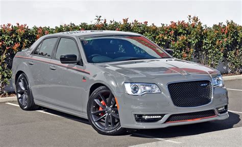 a grey car parked in a parking lot next to bushes and trees with orange ...