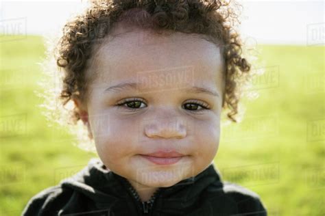 Close up of mixed race baby boy with curly hair - Stock Photo - Dissolve