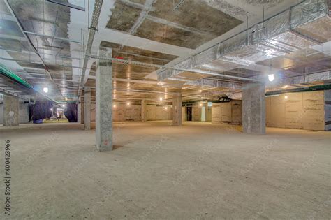 Underground parking in construction phase. Empty garage in basement of office building under ...