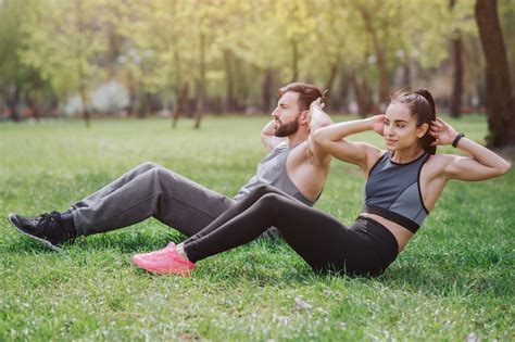 Strong And Powerful People Are Working Out Outside In Park. They Are Doing Abs Exercises. Young ...