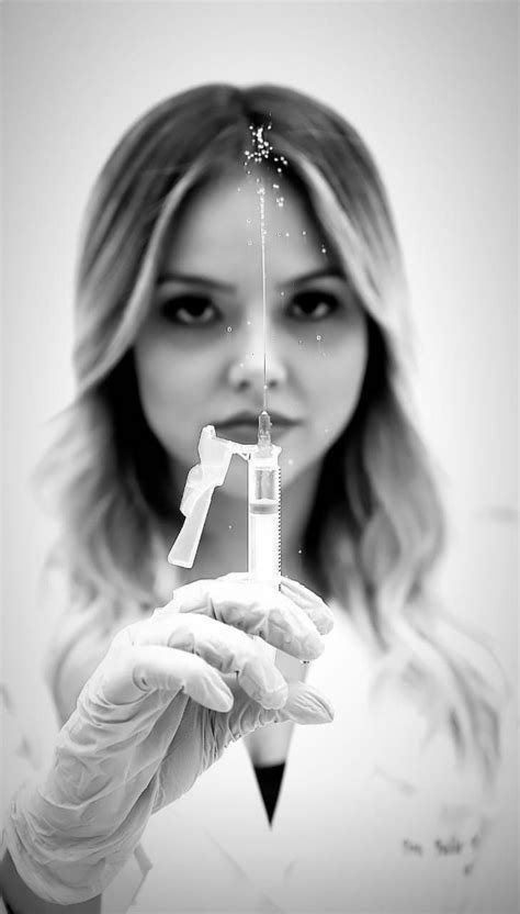 a woman in white gloves holding up a small bottle with liquid coming out of it