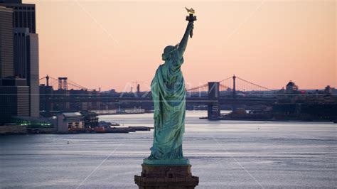 Statue of Liberty at sunrise, Brooklyn Bridge in the background, New ...