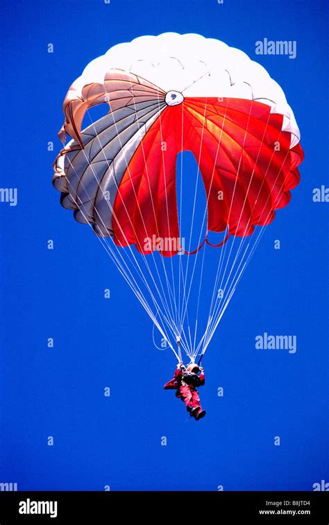 One Sky Diver skydiving with a Red and White Parachute in a Blue Sky Stock Photo - Alamy